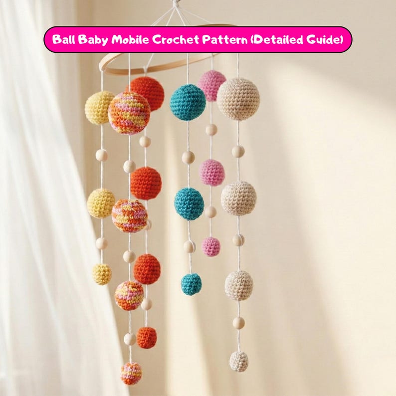 May include: A handmade baby mobile featuring crochet balls in various colors, including yellow, orange, pink, blue, and cream. The balls are suspended from a wooden hoop with wooden beads. The text "Ball Baby Mobile Crochet Pattern (Detailed Guide)" is visible.