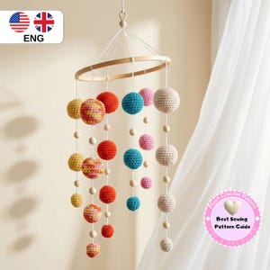 May include: A colorful crochet mobile with various sized spheres in shades of yellow, red, blue, and pink, suspended from a wooden ring. The mobile is designed for a nursery or children's room. The text in the image says "Best Sewing Pattern Guide".