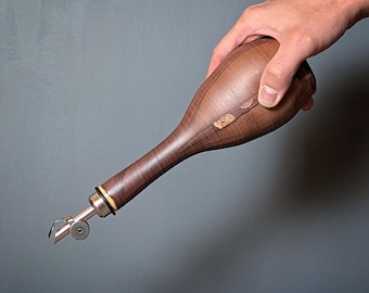 May include: A wooden olive oil bottle with a metal pour spout. The bottle is brown with a natural wood grain pattern.