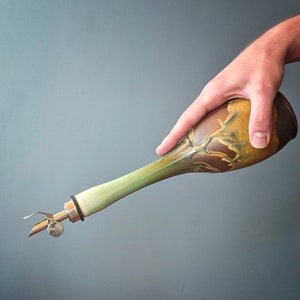 May include: A ceramic olive oil bottle with a green and brown glaze. The bottle has a metal pour spout and a hand-painted design.