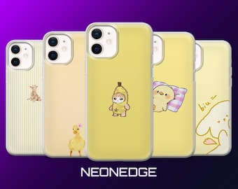 Puede incluir: Cinco fundas amarillas para teléfono con varios diseños. Una funda presenta una jirafa, otra un patito, una tercera un personaje con disfraz de plátano, una cuarta un pollito sobre una almohada y la última un personaje de dibujos animados. Fondo púrpura.
