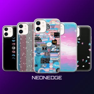Puede incluir: Una colección de fundas para teléfonos con varios diseños. Una funda presenta un diseño de fases lunares, otra tiene un patrón de estrellas brillantes, y una tercera muestra un collage con el texto "TRANSGENDER PRIDE" y "PRETTY BOY". Las fundas están en fila sobre un fondo púrpura.