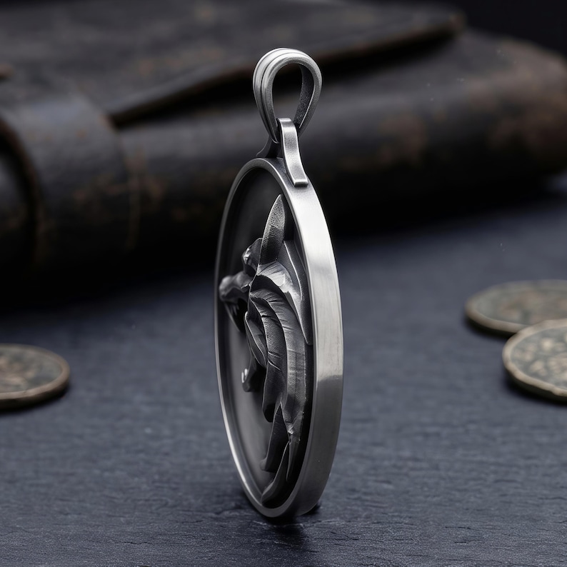 May include: A silver pendant featuring a detailed wolf head design. The oval-shaped pendant has a loop for a chain. The wolf's head is in profile, with intricate detailing on the fur and features. The pendant is displayed on a dark surface.