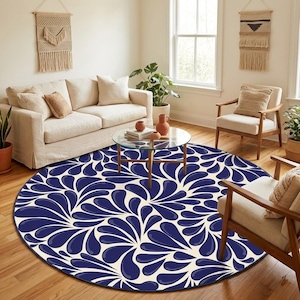 Puede incluir: Una alfombra redonda con un diseño de gotas azul marino y crema. La alfombra está colocada en un salón con un sofá, sillas y una mesa de centro. El diseño de la alfombra añade un elemento decorativo a la habitación.
