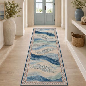 Peut inclure: Un long tapis de couloir rectangulaire présentant un motif ondulé dans des tons de bleu, bleu clair et crème. Le design inclut de petits motifs de poissons bleu foncé dans les vagues, encadré par une fine bordure orange et un bord bleu rayé.