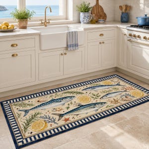 May include: A rectangular kitchen runner rug featuring a cream-colored background with a repeating pattern of blue fish, yellow lemon slices, green herbs, seashells, and starfish, all framed by a dark blue and white striped border.
