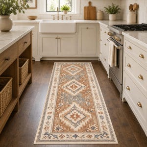 Könnte beinhalten: Ein rechteckiger Küchenläufer mit einem geometrischen Muster in Braun-, Creme-, Grau- und Blautönen. Der Teppich weist Rauten- und Blumenmotive auf und verleiht der Küche Wärme und Stil. Der Teppich liegt auf einem dunklen Holzboden.