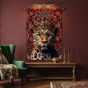 May include: A regal leopard portrait wearing a jeweled crown, set against a red patterned tapestry. The leopard's spotted coat contrasts with the ornate gold crown and the rich red background, creating a striking visual statement. The artwork is mounted on a wall.