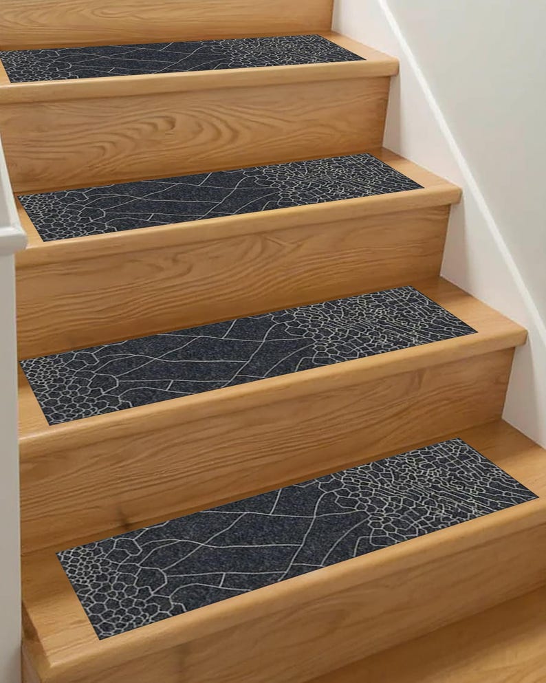 May include: Dark grey stair treads with a white, geometric pattern, installed on wooden stairs. The treads provide a decorative and functional element for home decor, with each tread measuring approximately 70 cm in length.