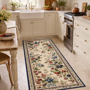 May include: A rectangular runner rug featuring a cream-colored background with a repeating pattern of colorful berries, including red strawberries, blue blueberries, and dark blackberries, accented by green leaves and a dark blue border.