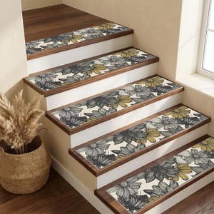 May include: Stair treads with a floral design. The treads feature a cream-colored background with a pattern of gray and yellow flowers. The edges of the treads are a dark brown, and the stairs are white.