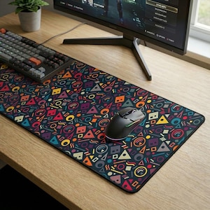 Può includere: Un tappetino per mouse rettangolare con uno sfondo scuro e un colorato motivo geometrico di triangoli, cerchi e altre forme. Un mouse da gioco nero è posizionato sul tappetino, accanto a una tastiera. Il tappetino è su una scrivania di legno.