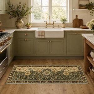 Puede incluir: Alfombra de cocina rectangular con diseño floral. La alfombra presenta un borde verde oscuro y un centro crema con grandes flores amarillas y pequeños detalles florales. La alfombra está colocada sobre un suelo de madera en una cocina.