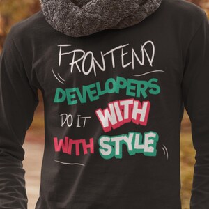 May include: Black long-sleeve shirt with the text "FRONTEND DEVELOPERS DO IT WITH STYLE" in white, green, and red. The shirt is worn by a person with a gray scarf. The text is in a playful, handwritten style.