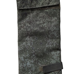 May include: A rectangular pouch with a digital camouflage pattern in shades of green and gray. It features a black plastic clip at the top and a velcro strap closure. The pouch is designed for carrying small items.