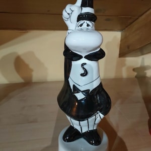 Può includere: Statuetta Bialetti in ceramica bianca e nera, raffigurante un personaggio a fumetti in smoking e cappello, con una mano alzata. La base della statuetta riporta la scritta "BIALETTI".