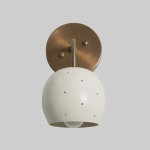 Aplique minimalista de pared con pantalla esférica blanca, lámpara de estilo moderno de mediados de siglo, hecha de latón.