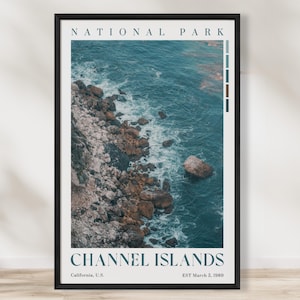 May include: A framed print depicting the Channel Islands National Park coastline. The image shows a rocky shore meeting the turquoise sea. The words "NATIONAL PARK" and "CHANNEL ISLANDS" are printed at the top and bottom, with location and date details included.
