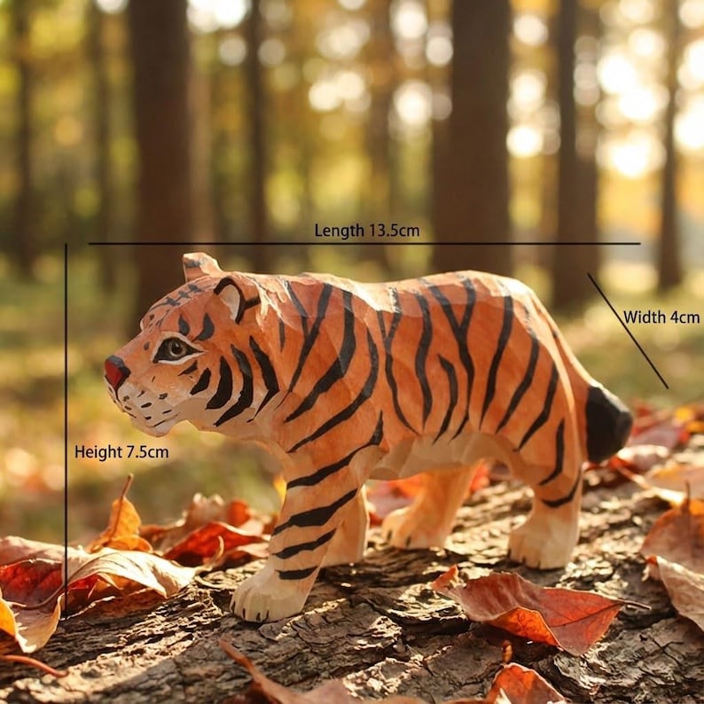 K&ouml;nnte beinhalten: Handgeschnitzte Holz-Tigerfigur, 13,5 cm lang, 4 cm breit und 7,5 cm hoch. Der Tiger hat orange und schwarze Streifen, eine rote Nase und steht auf einer Holzoberfl&auml;che mit Bl&auml;ttern. Die Figur ist ein Dekorationsartikel.