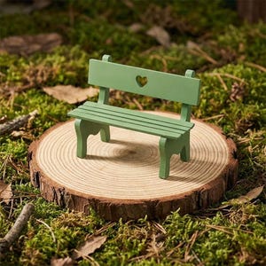 May include: A small, green wooden bench with a heart-shaped detail in the backrest. It's placed on a round wooden slice, set amidst green moss and leaves. A delightful decorative bench.