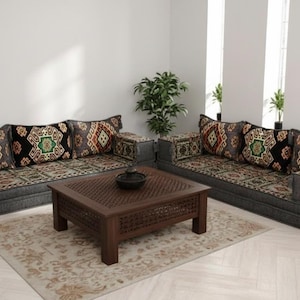 May include: Living room set featuring two gray sofas with patterned cushions and a matching coffee table. The cushions and sofa bases have a dark gray color. The coffee table is brown with a carved design. A beige rug is under the table.