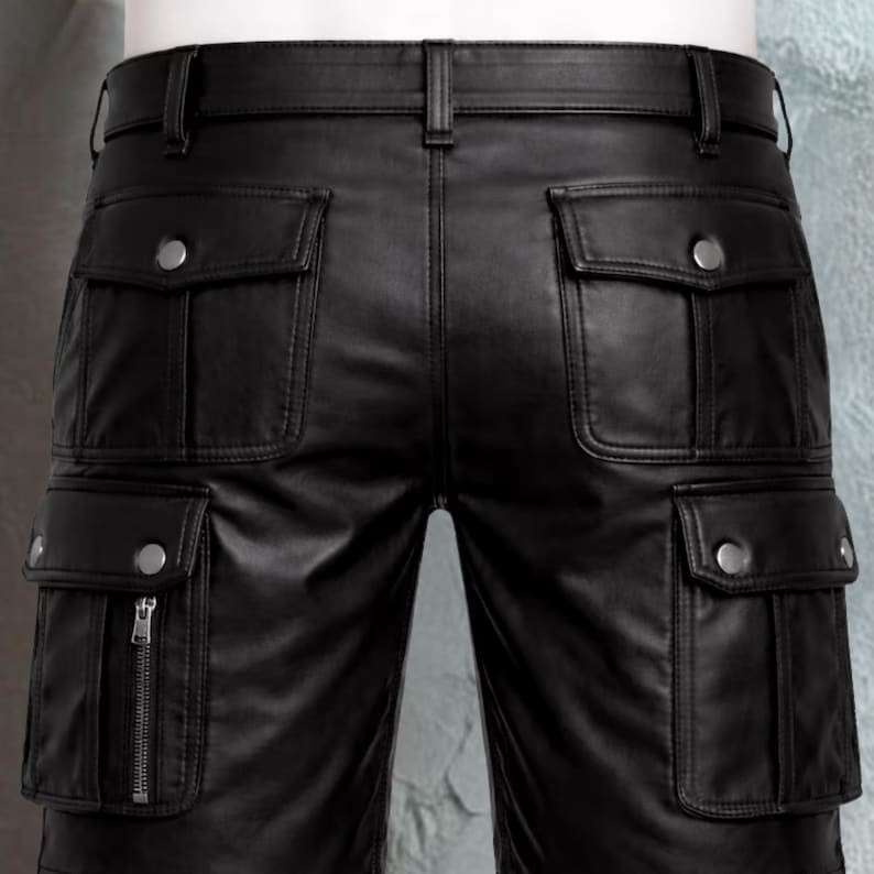 Pu&ograve; includere: Pantaloni cargo in pelle nera con multiple tasche e dettagli con bottoni argentati. I pantaloni hanno una cintura con passanti e una chiusura con cerniera su una delle tasche. La pelle appare liscia e il design &egrave; su misura.
