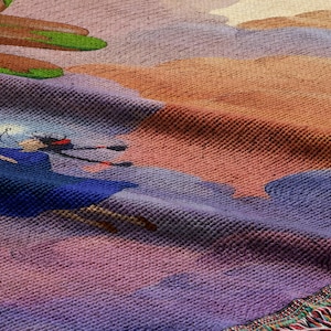 The image is a close-up of a colorful textile with a painting of a woman in a blue dress and hat.