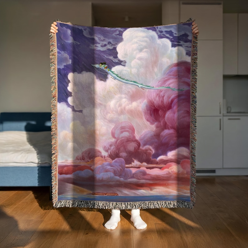 A person is holding up a large, colorful tapestry depicting a dragon flying through a cloudy sky.