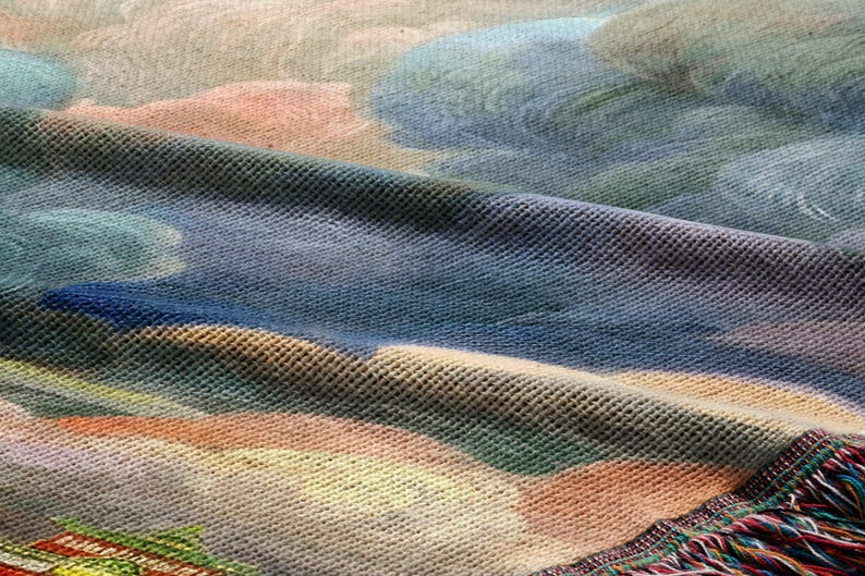The image is a close-up of a textured fabric with a colorful, abstract pattern. The fabric appears to be a woven material, possibly a blanket or a textile. The pattern on the fabric is a mix of various colors and shapes, creating a visually interesting and dynamic design.