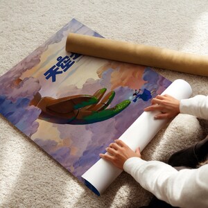A person is rolling up a poster with a colorful illustration of a bird and clouds on it, which appears to be a poster or artwork.