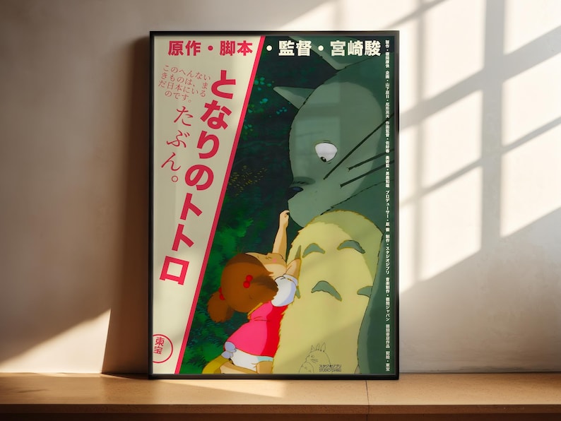 The image is a framed poster featuring an illustration of a young girl interacting with a large, green creature, possibly a cat or a dragon. The poster has Japanese text on it, which appears to be related to the story or characters depicted in the illustration.