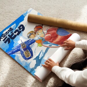 A person is holding a roll of paper and a poster featuring an illustration of a blue airplane and two cartoon characters.