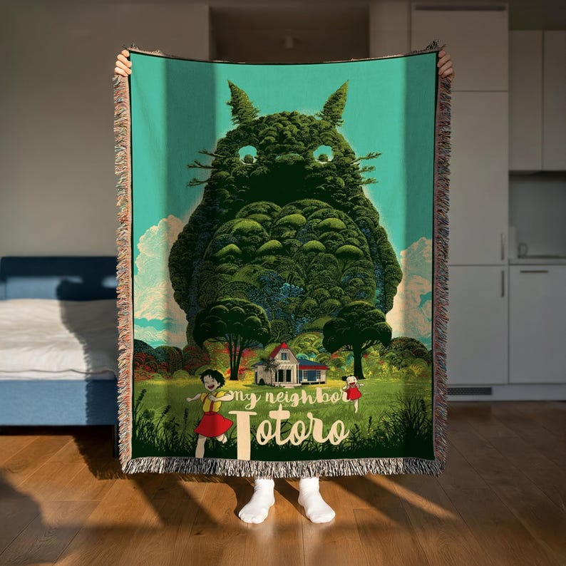 A person is holding up a large, colorful tapestry depicting a whimsical scene with a large, green creature resembling a cat or monster, surrounded by a lush, forest-like landscape.