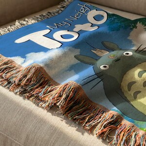 A colorful throw blanket with a cartoon character design, featuring the text "My Neighbor Totoro" on it.