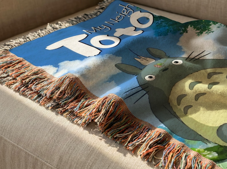 A colorful throw blanket with a cartoon character design, featuring the text "My Neighbor Totoro" on it.