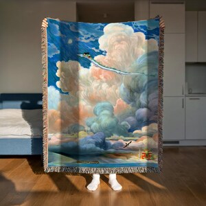 A person is holding up a large, colorful tapestry depicting a serene landscape with a cloudy sky, a bird, and a landscape with mountains and a river.