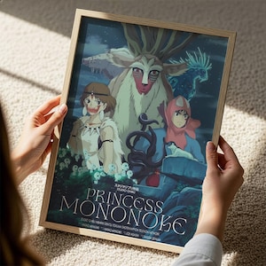 A person is holding a framed poster of the animated film "Princess Mononoke". The poster features the main characters from the movie, including Princess Mononoke, a young girl, and a dragon-like creature. The poster also includes the title of the film and some additional text.