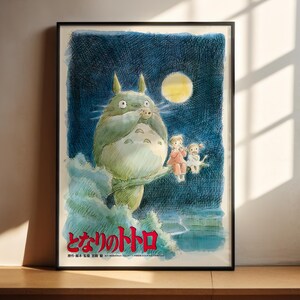 The image is a framed poster featuring a whimsical illustration of a large, green creature with horns and a yellow moon in the background, accompanied by two smaller figures.