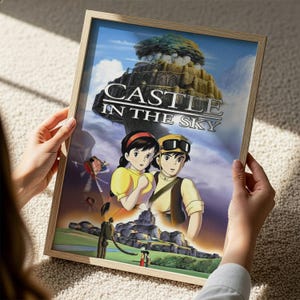 A person is holding a framed poster of the animated film "Castle in the Sky".