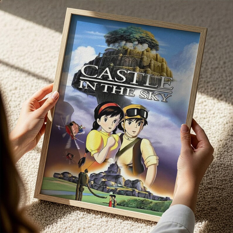 A person is holding a framed poster of the animated film "Castle in the Sky".