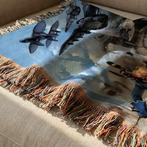 a close-up view of a colorful blanket or throw with a unique design, including various objects such as airplanes, a person, and other abstract shapes.