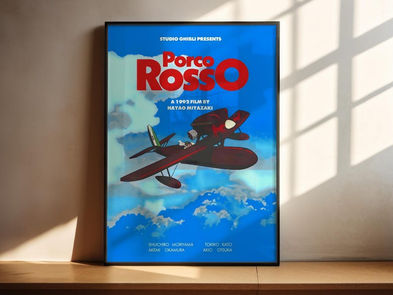 A poster for the 1995 film "Porco Rosso" by Hayao Miyazaki, featuring an illustration of a red airplane flying through a blue sky with clouds.