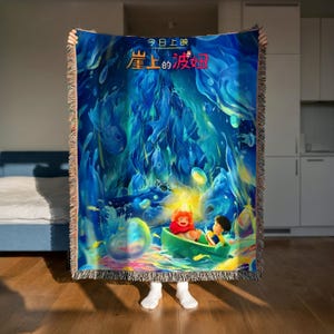 A person is holding up a colorful, vibrant blanket with an illustration of two characters, one of whom is a small child, in a fantastical underwater scene.