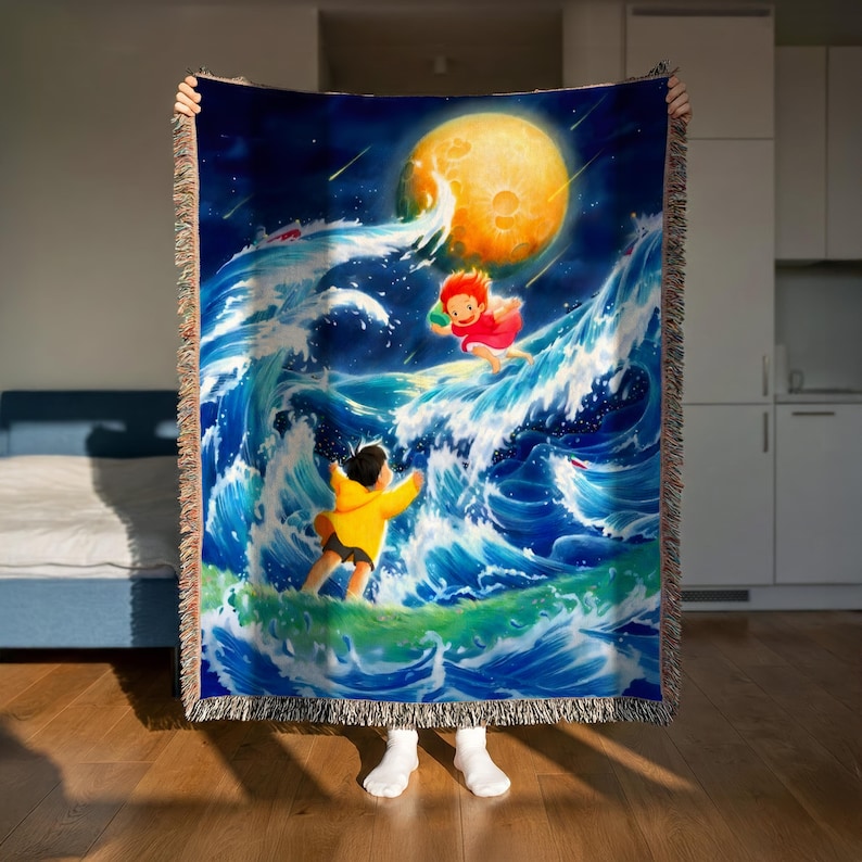 A person is holding up a large, colorful tapestry depicting a scene with a large moon, a person in a yellow outfit, and a person in a red outfit, all set against a backdrop of crashing waves.