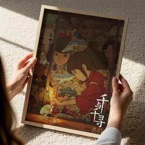 A person is holding a framed poster featuring an illustration of a young girl surrounded by various characters and scenes.