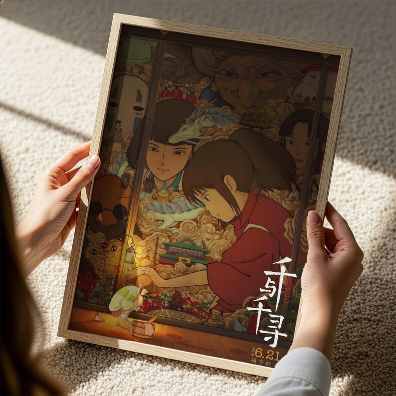 A person is holding a framed poster featuring an illustration of a young girl surrounded by various characters and scenes.