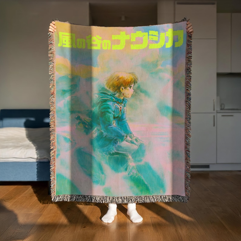 A person is holding up a colorful blanket with a cartoon character on it, which appears to be a piece of artwork or a decorative item.
