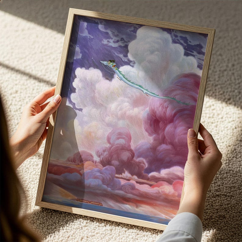 A person is holding a framed painting depicting a fantastical scene with a dragon-like creature soaring through a vibrant, cloud-filled sky.