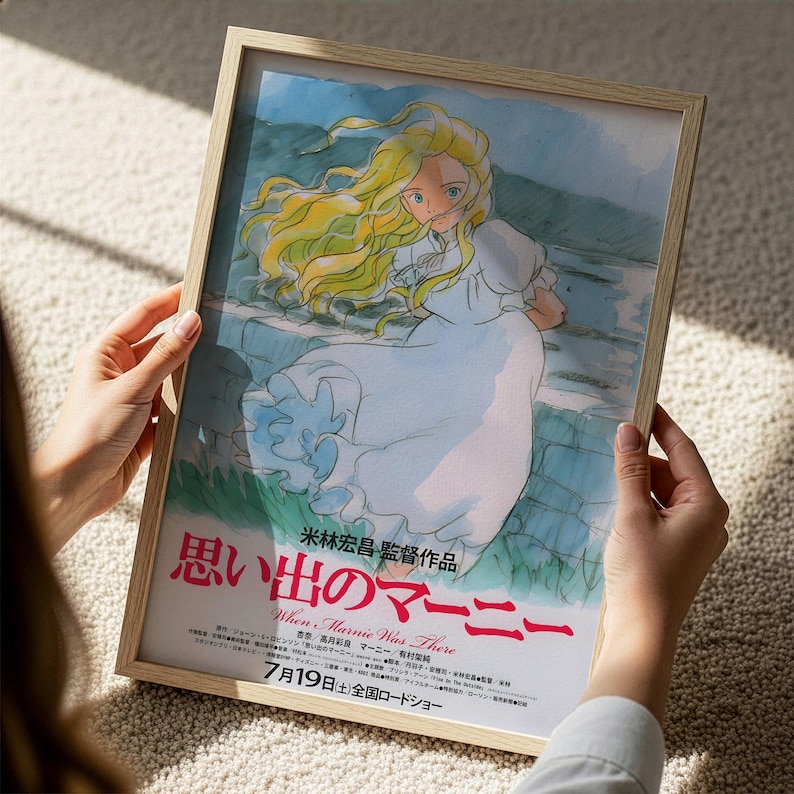 A person is holding a framed poster featuring an illustration of a young girl with long blonde hair, wearing a white dress, and standing in a natural setting.