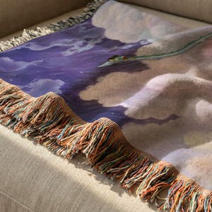 a close-up view of a colorful blanket with a dragon design on it, resting on a beige couch.